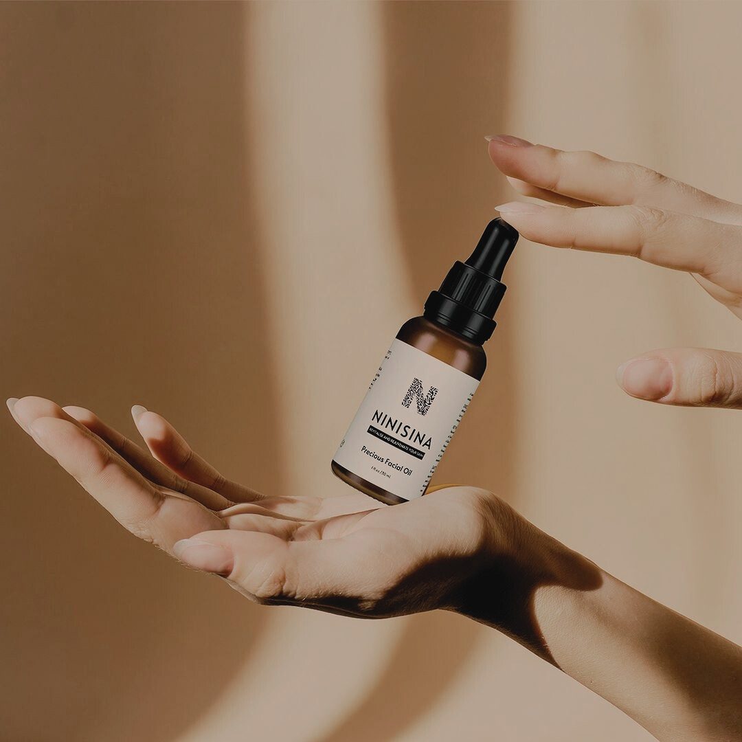 Two hands holding a bottle of facial oil