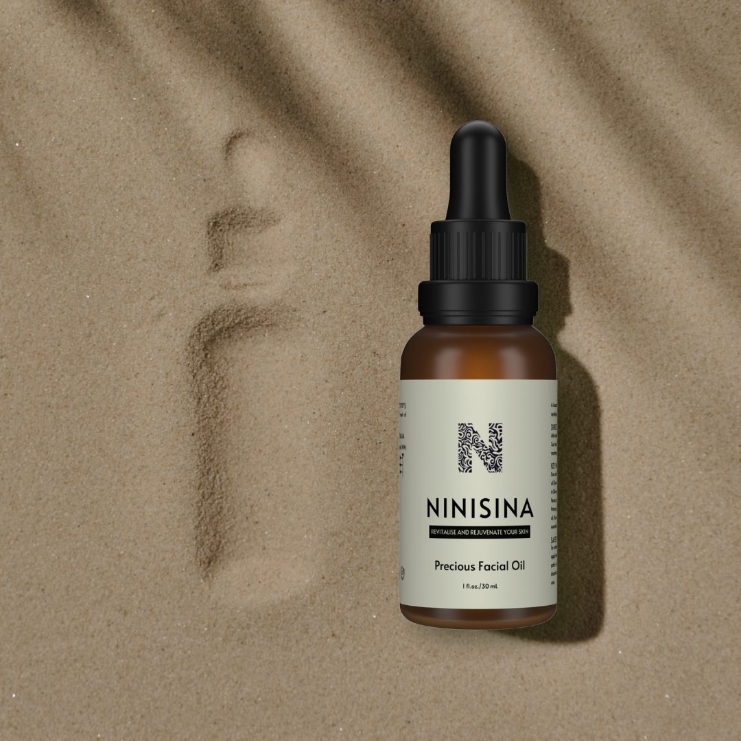 Precious Facial Oil resting on rippled sand