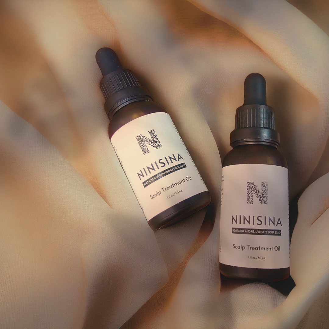 Two bottles of Scalp Treatment Oil on folds of pale silk